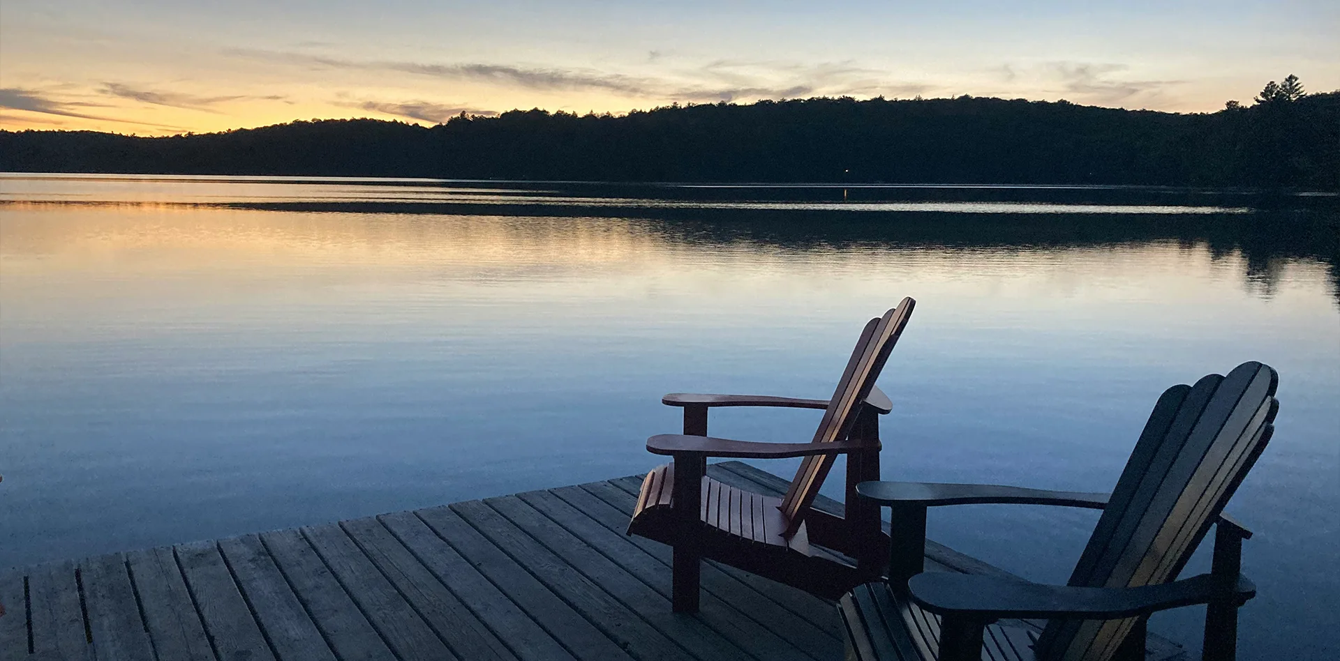 Empty chairs on a dock by calm water | Bala Bay Inn Retreats