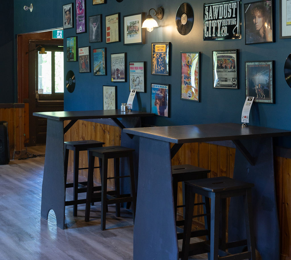 Bar area with 2 tables and signs on the wall at the Bala Bay Inn Beer Parlour and Ghost Kitchen