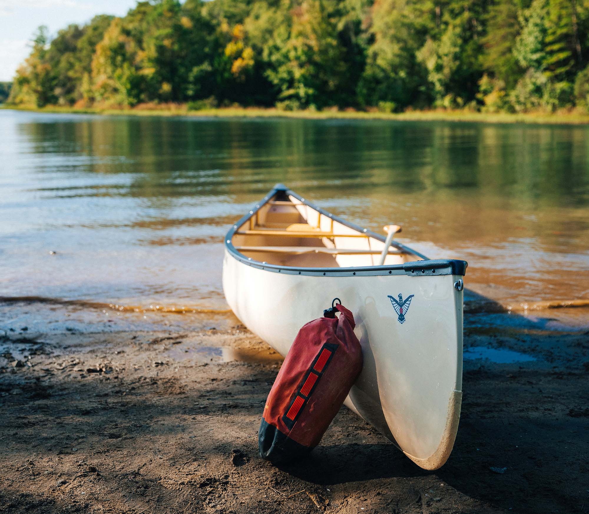 Canoe on the shore of a lake with a red bag leaning against it looking out at the beautiful scenery | Bala Bay Inn Outdoors