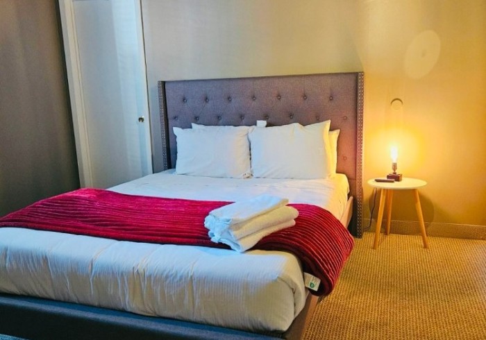 Queen Suite room with a queen bed and bedside table with a lamp on | Bala Bay Inn